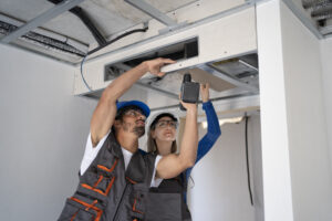 Dos personas instalando maquinaria en el techo 
